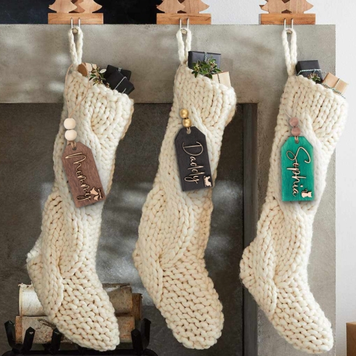 πλεκτές κάλτσες κερο'υ κραμασμένες μπροστά σε τζάκι με ξύλινα καρτελάκια με ονόματα για τα χριστούγεννα
