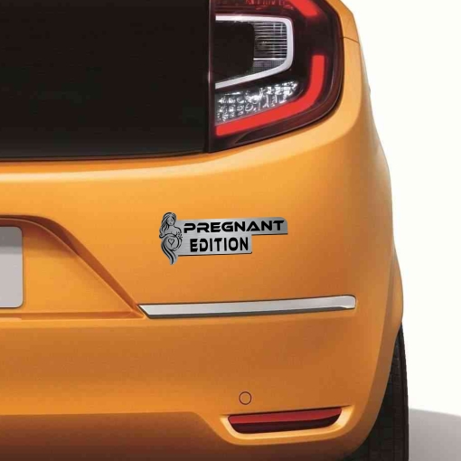Αυτοκόλλητο Pregnant Edition σε μεταλλικό φινίρισμα, με σιλουέτα εγκύου, τοποθετημένο στο πορτ-μπαγκάζ ενός πορτοκαλί αυτοκινήτου.