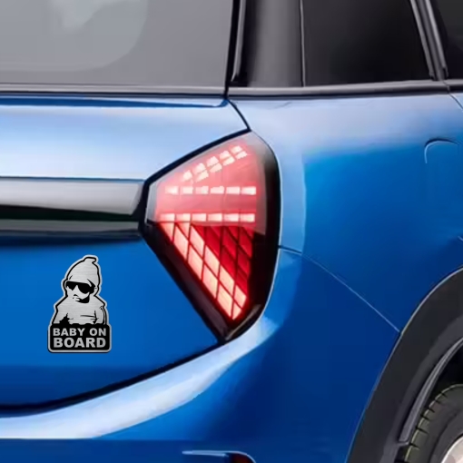Αυτοκόλλητο Baby on Board σε μεταλλικό φινίρισμα, με μωρό που φοράει γυαλιά ηλίου, τοποθετημένο στο πίσω μέρος ενός μπλε αυτοκινήτου.
