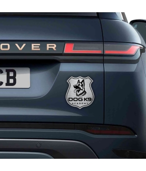 Αυτοκόλλητο Dog K9 Academy σε σχήμα αστυνομικής κονκάρδας με κεφαλή Γερμανικού Ποιμενικού, σε μεταλλικό φινίρισμα, τοποθετημένο στο πίσω μέρος ενός σκούρου SUV.