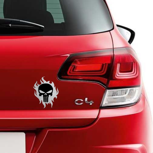 Αυτοκόλλητο κρανίο Punisher με φλόγες, μαύρο και μεταλλικό φινίρισμα, τοποθετημένο στο πορτ-μπαγκάζ ενός κόκκινου αυτοκινήτου.